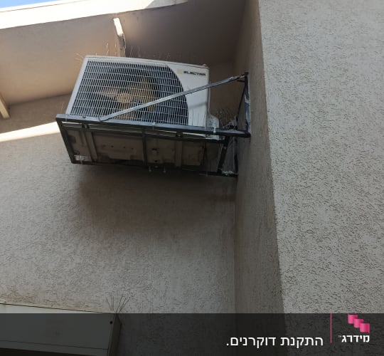 מזגן מותקן על קיר עם דוקרנים להרחקת יונים